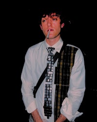 a man wearing a plaid tie and smoking a cigarette